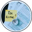 tax documents with a tax time post-it note and a clock.